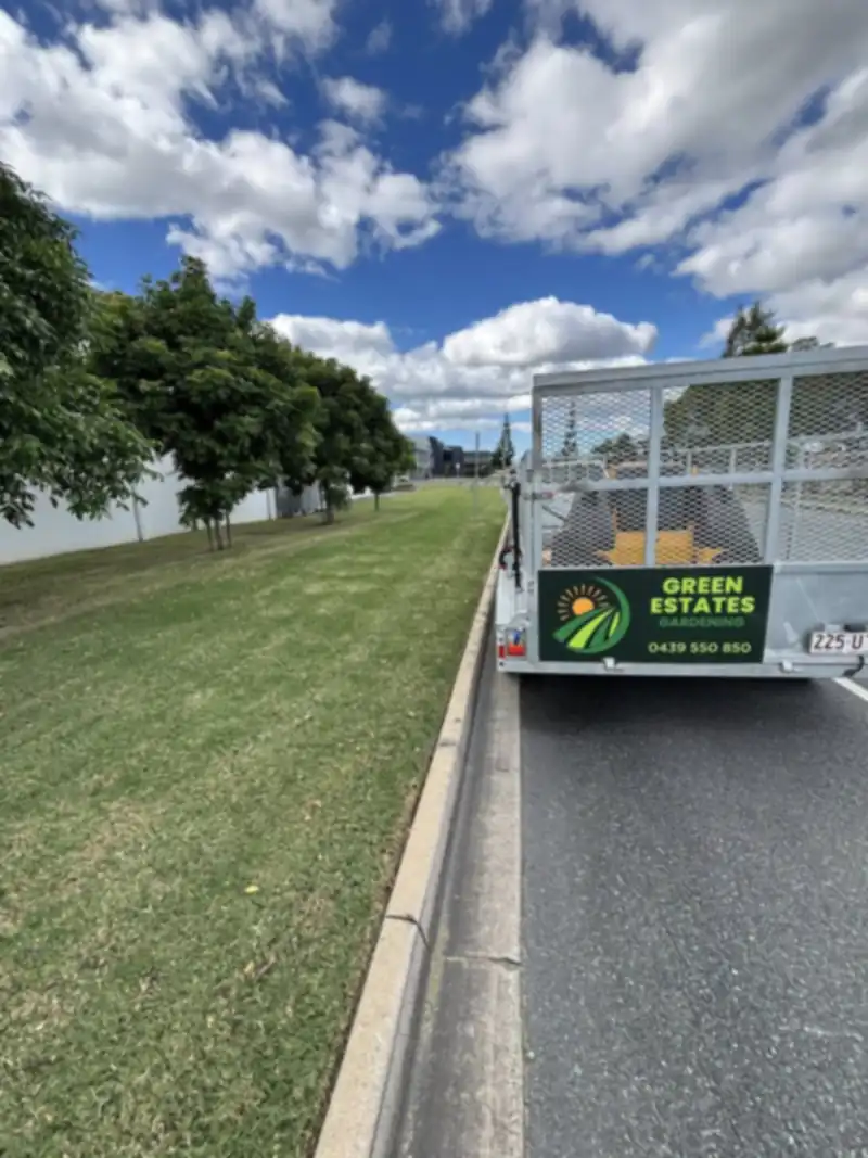Green Estates Gardening ute and branded trailer parked on a Moreton Bay street